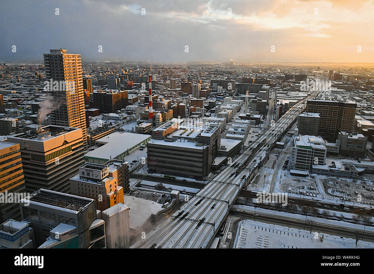 Panorama della città con orange grattacielo soleggiati e ferrovie in inverno, Sapporo, Hokkaido, Giappone Foto Stock