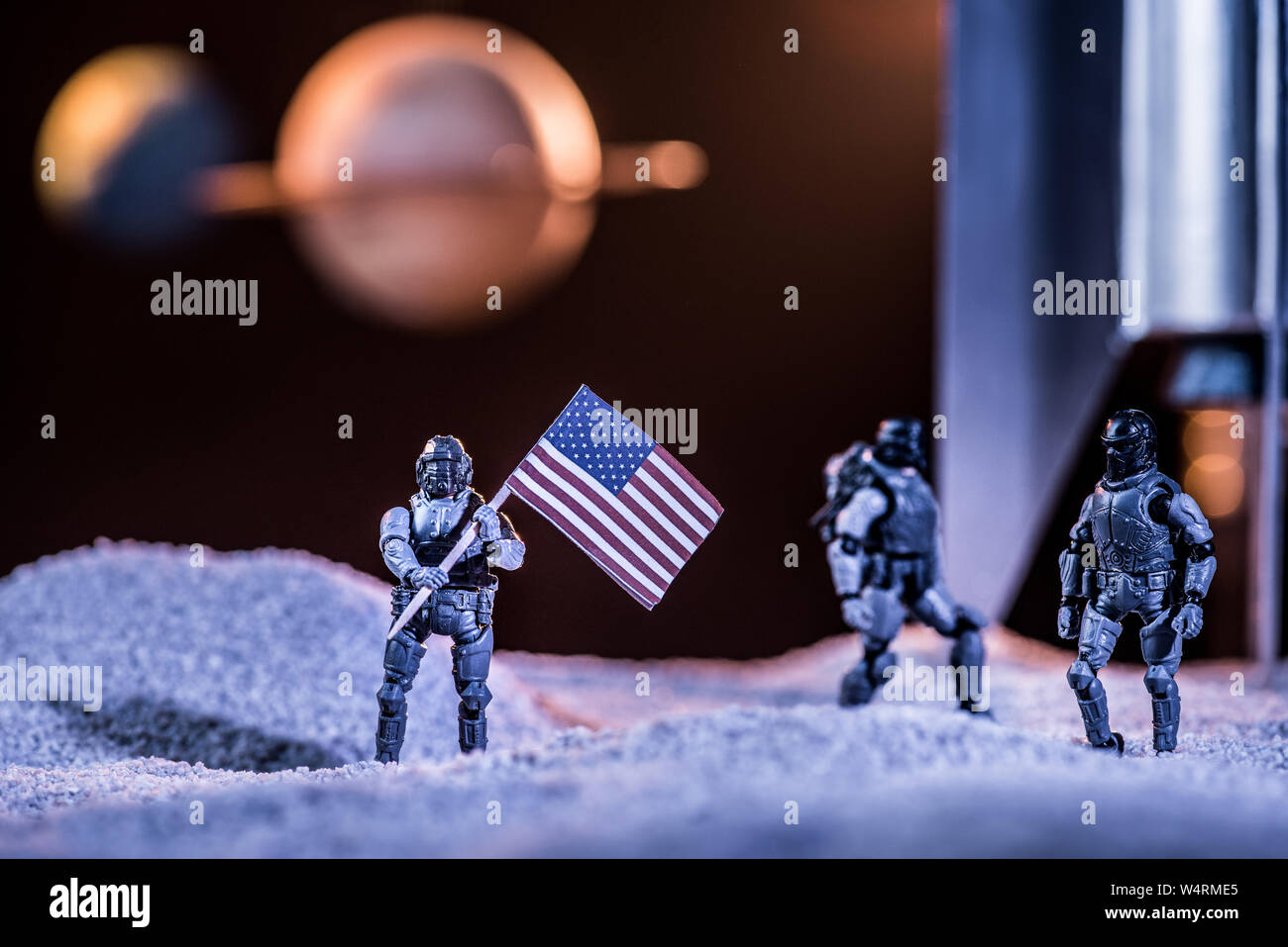 Messa a fuoco selettiva di astronauti giocattolo holding bandiera americana nello spazio vicino a razzo Foto Stock