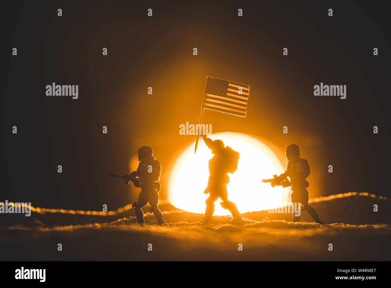 Messa a fuoco selettiva di toy soldiers sagome con pistole e bandiera americana camminando sul pianeta con sun sullo sfondo Foto Stock