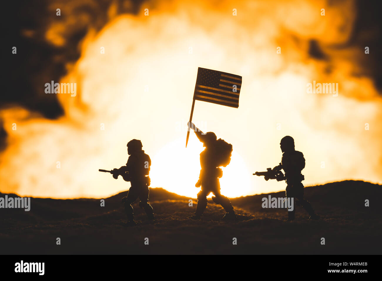 Toy Soldiers sagome con pistole e bandiera americana camminando sul pianeta con Sun in fumo sullo sfondo Foto Stock