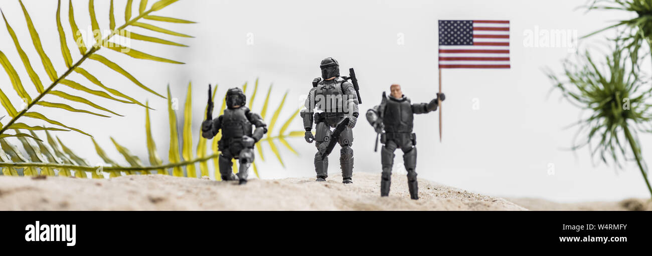 Panoramica di toy soldiers holding bandiera americana sulla duna di sabbia Foto Stock