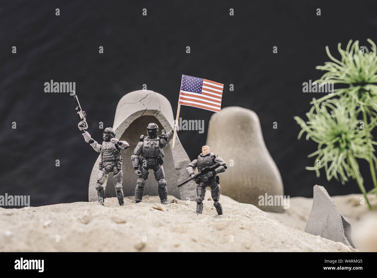 Messa a fuoco selettiva di soldatini con pistole e bandiera americana in piedi vicino grotte sulla duna di sabbia Foto Stock