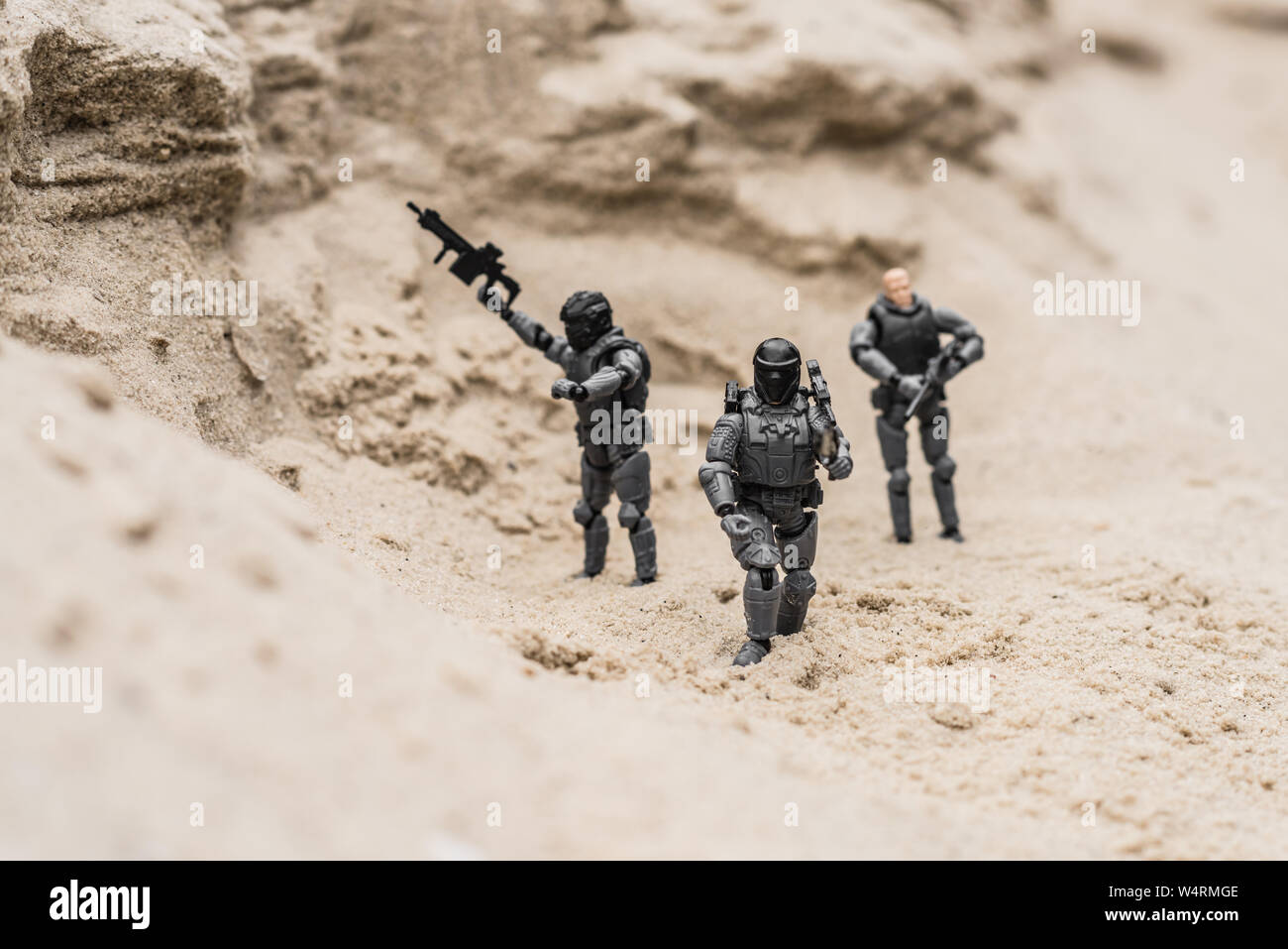 Messa a fuoco selettiva del giocattolo di plastica soldati sulle dune di sabbia con le pistole Foto Stock