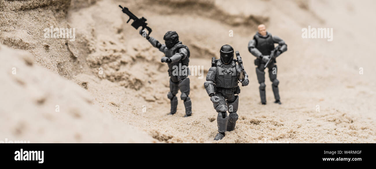 Messa a fuoco selettiva del giocattolo di plastica soldati sulle dune di sabbia con le pistole, scatto panoramico Foto Stock