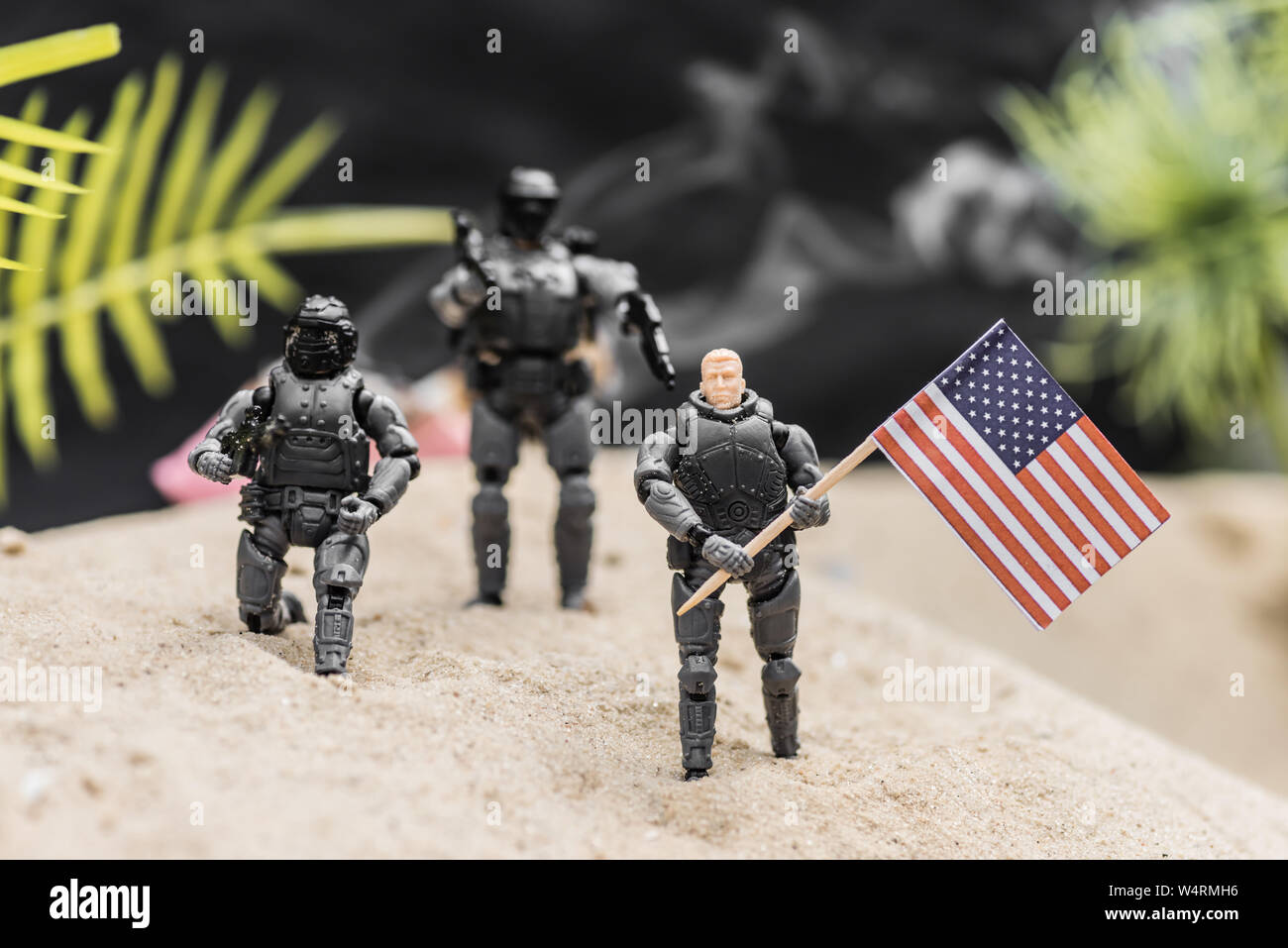 Messa a fuoco selettiva di soldatini con pistole holding bandiera americana sulla duna di sabbia Foto Stock