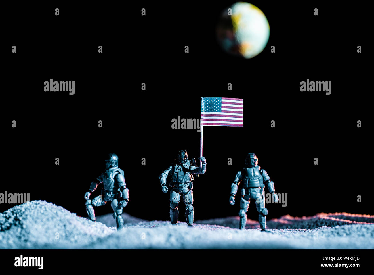 Toy Soldiers in piedi con la bandiera degli Stati Uniti sul pianeta nello spazio su sfondo nero con il pianeta Terra Foto Stock