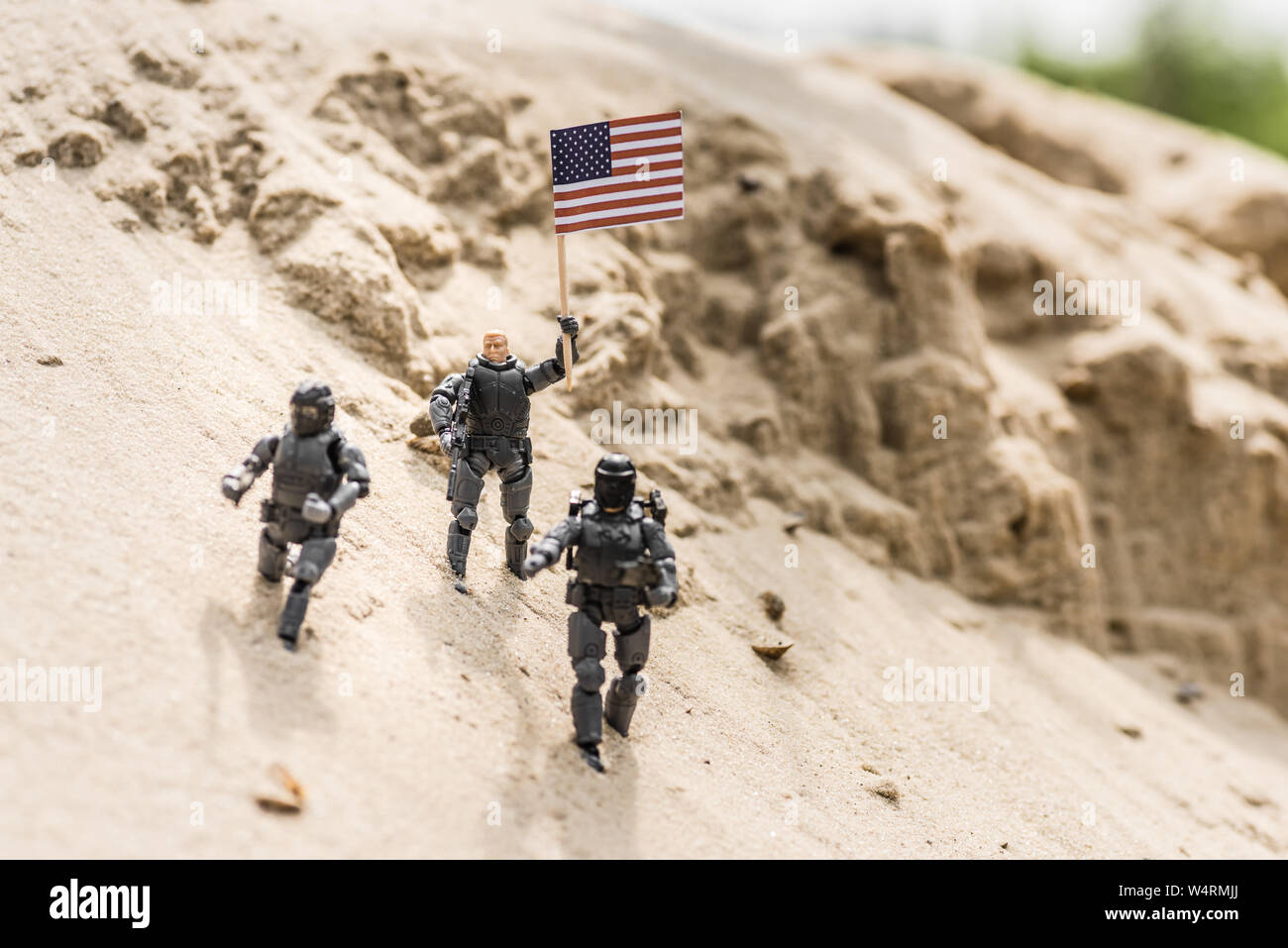 Toy Soldiers con arma permanente sulla sabbia e azienda bandiera americana Foto Stock