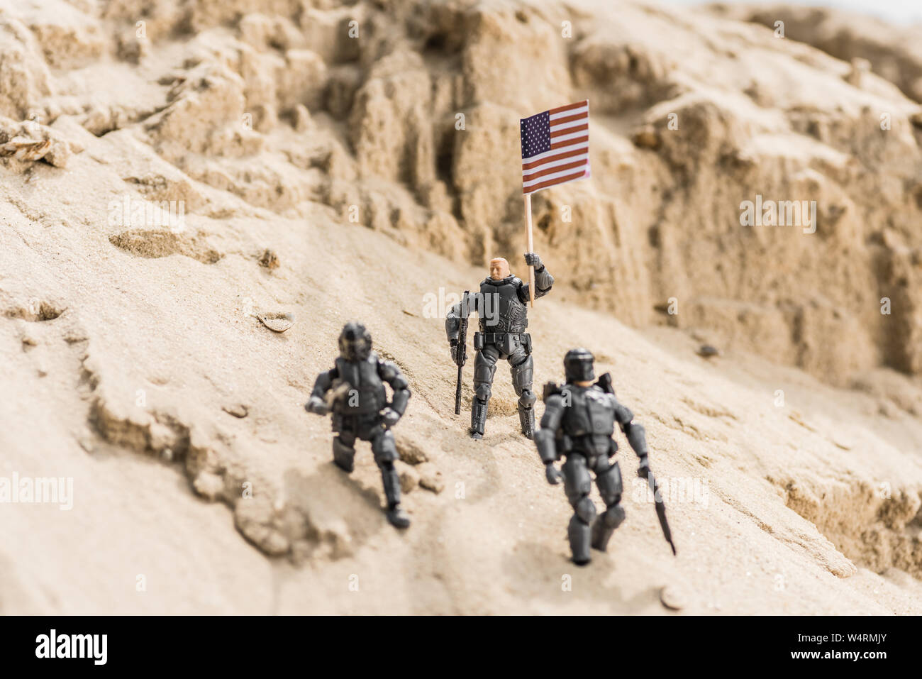 Toy soldati armati permanente sulla sabbia e azienda bandiera americana Foto Stock