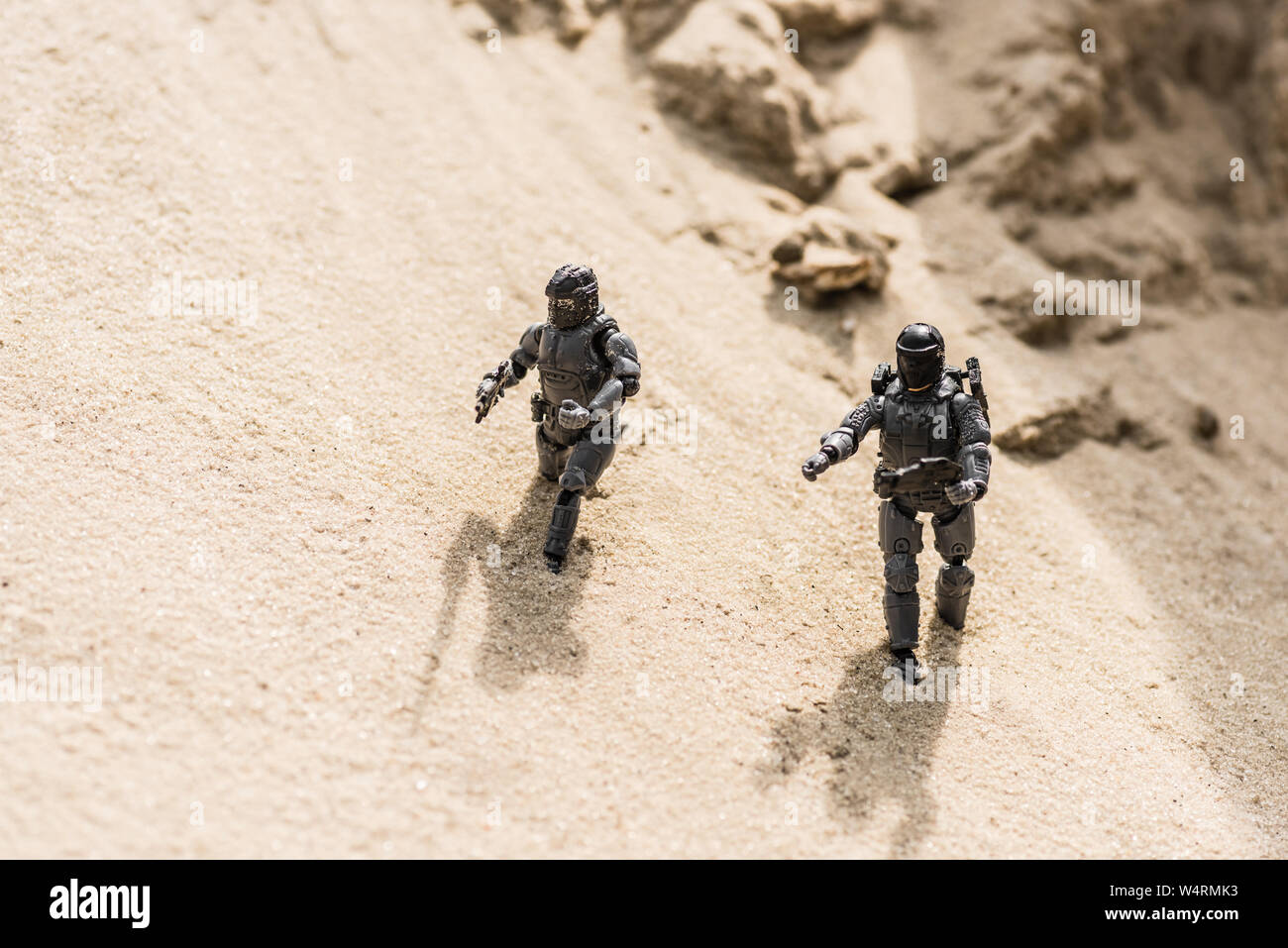 Tiny toy soldiers sulla sabbia con le ombre in luce diurna Foto Stock