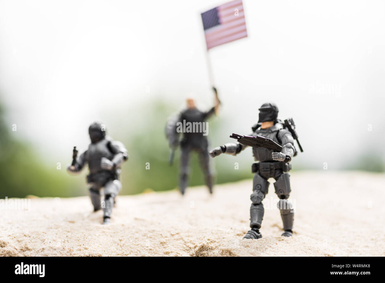 Messa a fuoco selettiva di soldatini con arma e la bandiera americana sulla sabbia Foto Stock