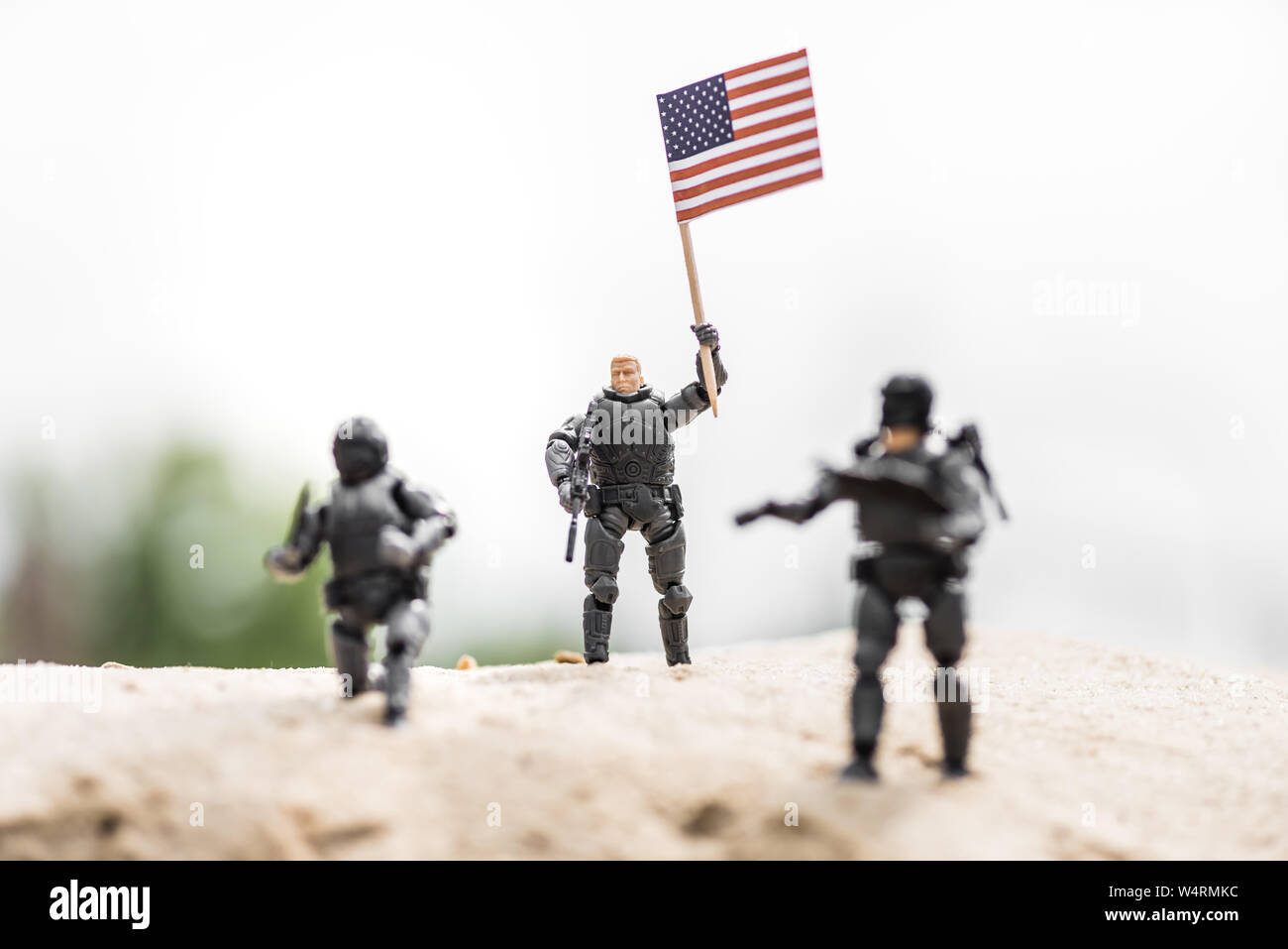 Messa a fuoco selettiva del soldatino con arma holding bandiera americana sulla sabbia Foto Stock