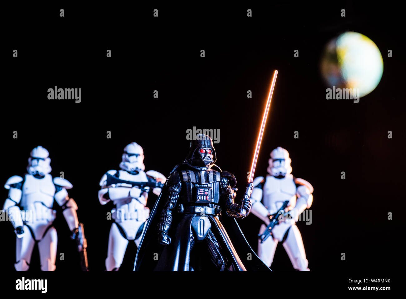 Kiev, Ucraina - 25 Maggio 2019: messa a fuoco selettiva di bianco imperial stormtroopers con pistole e Darth Vader con spada laser con il pianeta Terra su backgroun Foto Stock