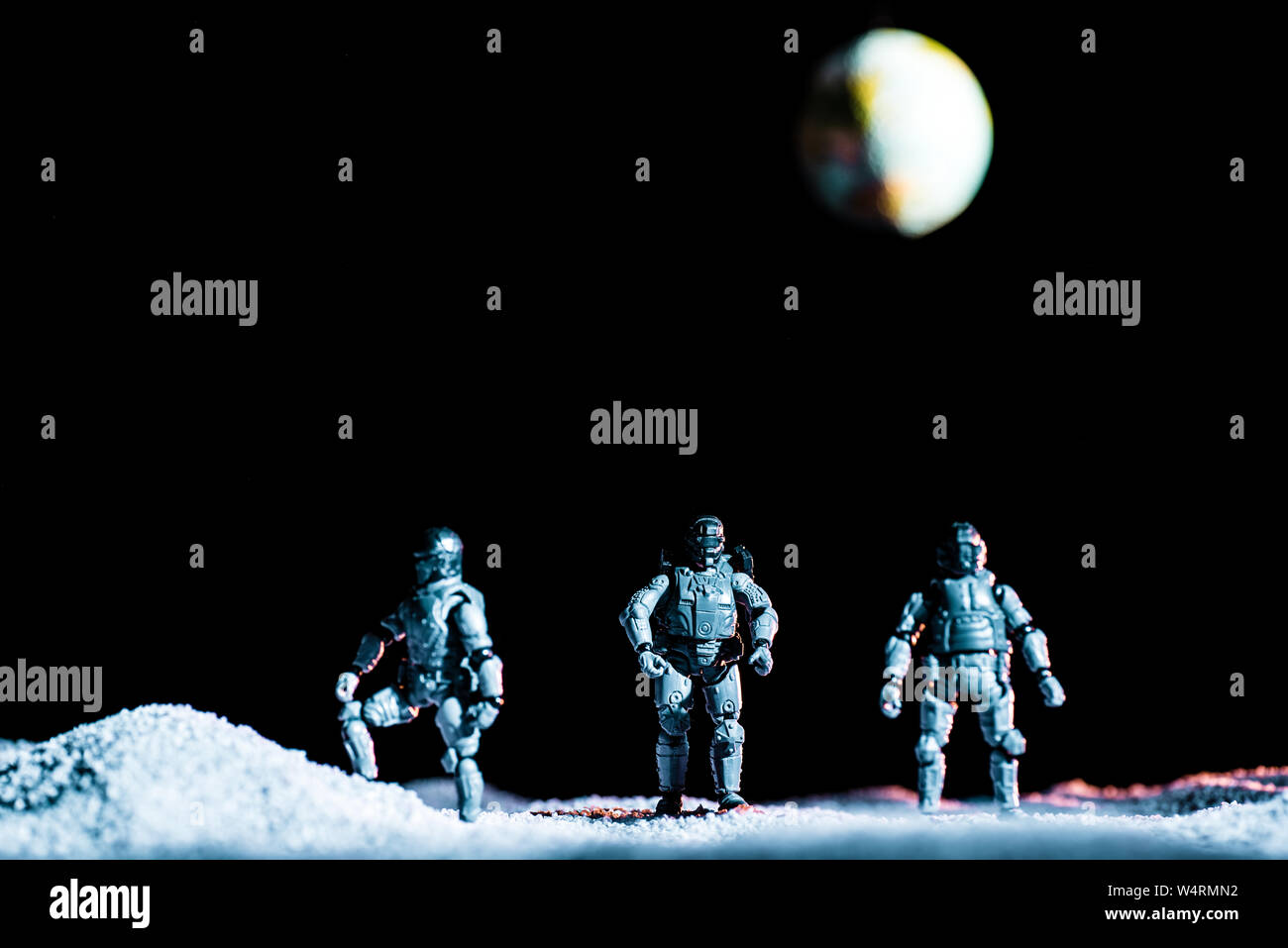 Toy Soldiers in piedi sul pianeta nello spazio su sfondo nero con il pianeta terra Foto Stock