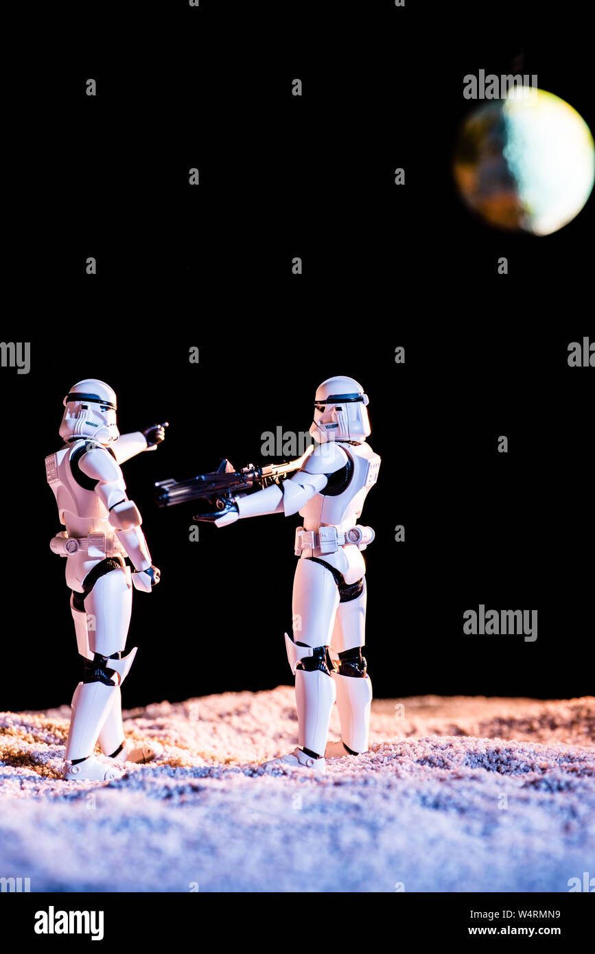Kiev, Ucraina - 25 Maggio 2019: bianco imperial stormtrooper mirando con la pistola a un altro su sfondo nero con il pianeta Terra Foto Stock