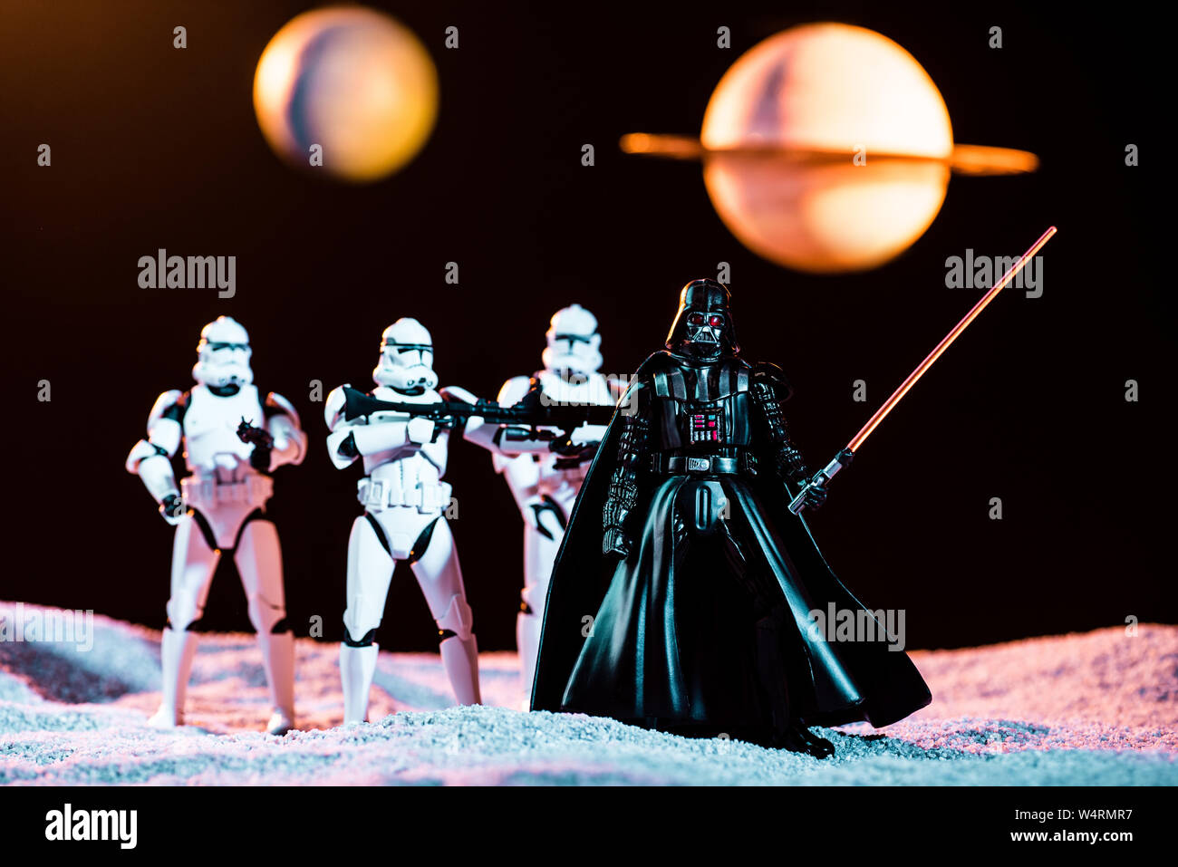 Kiev, Ucraina - 25 Maggio 2019: bianco imperial stormtroopers con pistole e Darth Vader con spada laser con i pianeti sullo sfondo Foto Stock