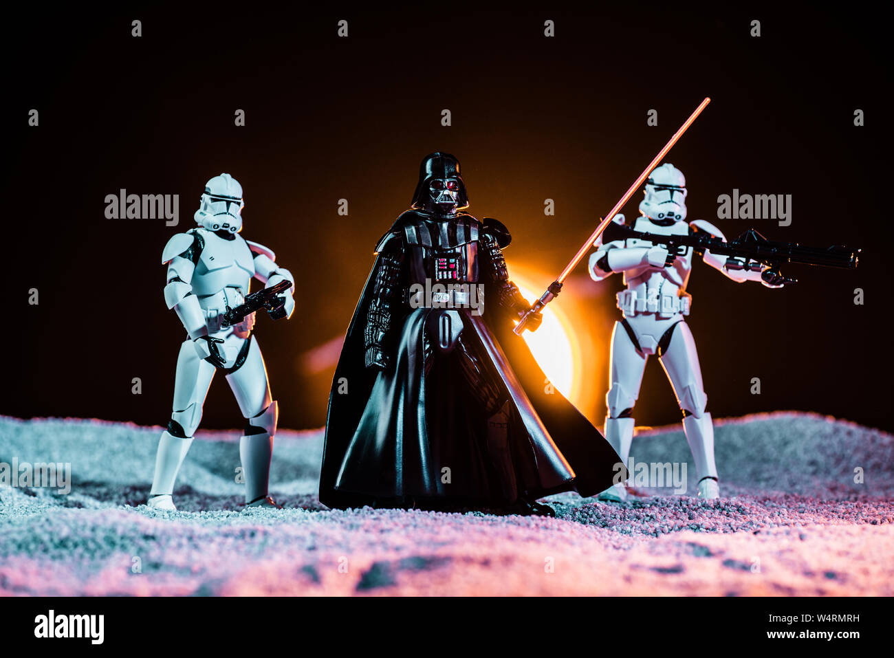 Kiev, Ucraina - 25 Maggio 2019: bianco imperial stormtroopers con pistole e Darth Vader con spada laser su sfondo nero con Sun Foto Stock