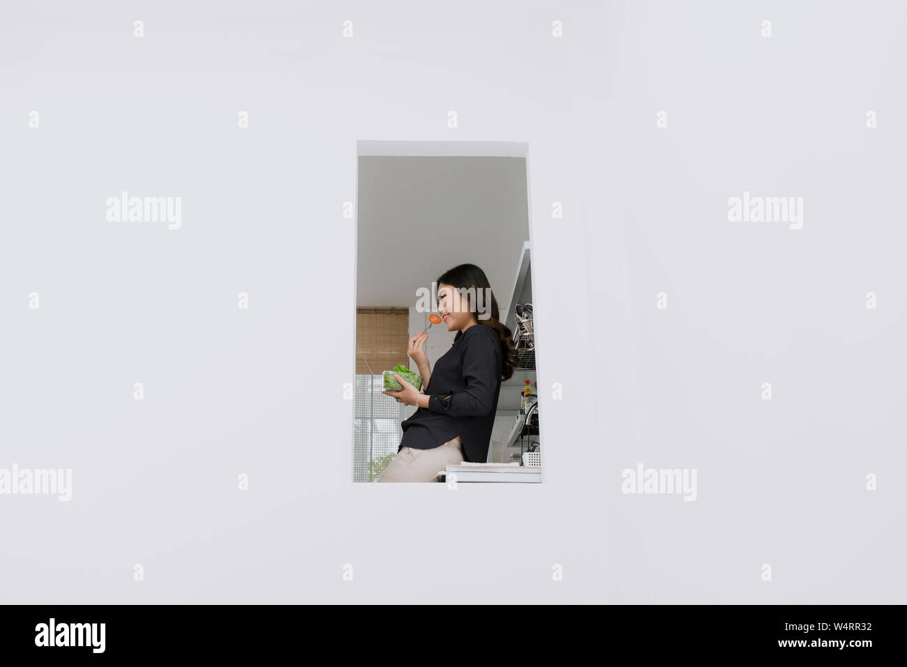 Dieta sana. Bella donna sorridente mangiare fresca insalata di organico nella cucina moderna. Mangiare sano, il cibo e il concetto di stile di vita. Salute, bellezza, dietin Foto Stock