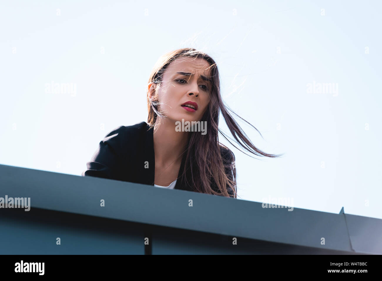 Giovane imprenditrice, affetti da paura delle altezze, guardando verso il basso tetto Foto Stock
