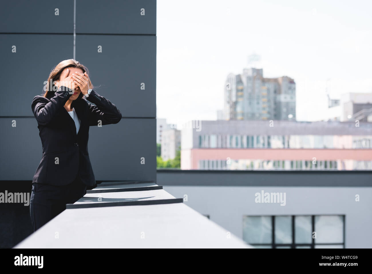 Giovane imprenditrice, affetti da paura delle altezze, in piedi sul tetto e che copre il viso con le mani Foto Stock