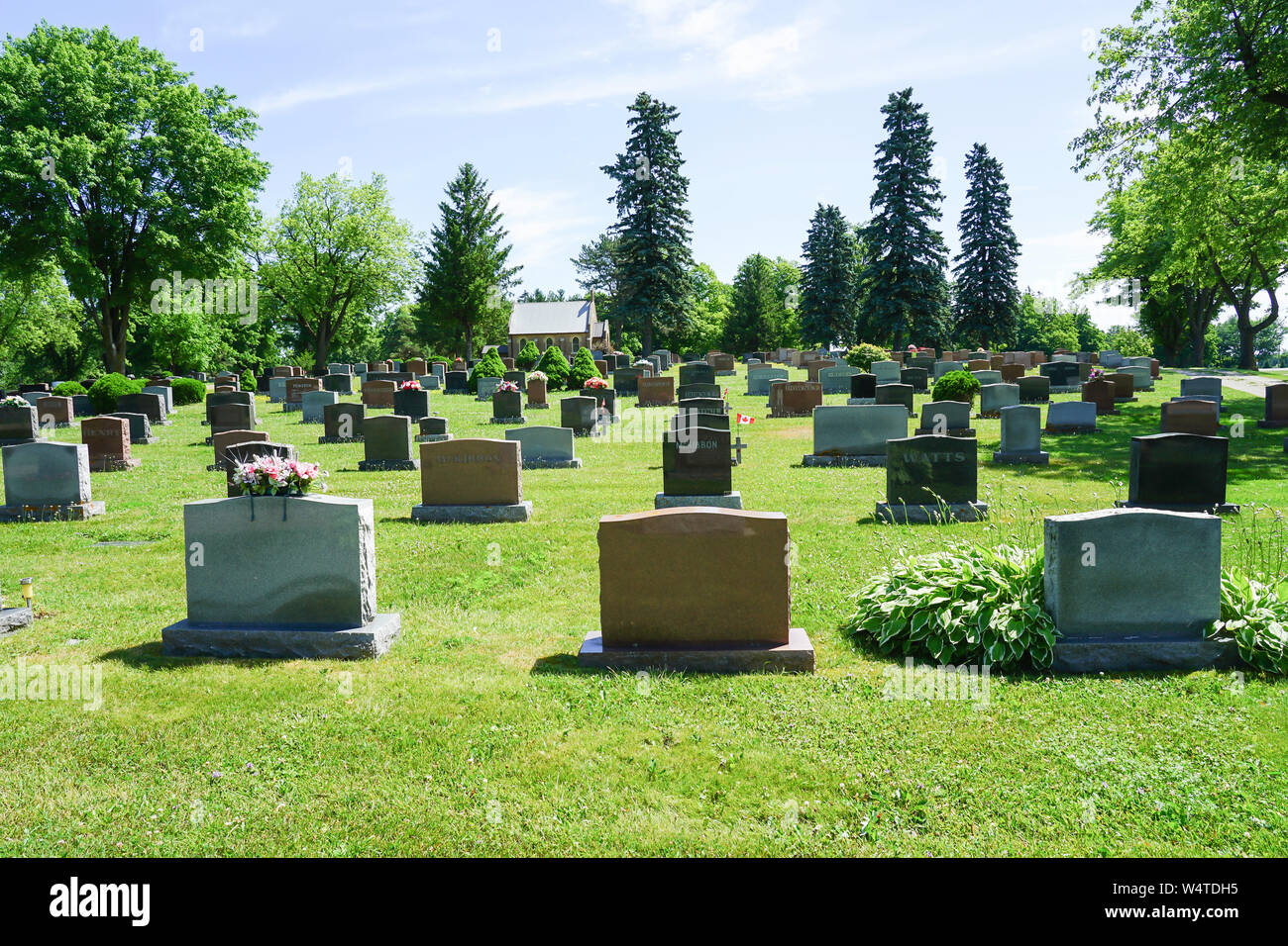 Un paese pittorica cimitero vicino Sherburne, Ontario, Canada con un sacco di fiori e di Nizza cantieri grave Foto Stock