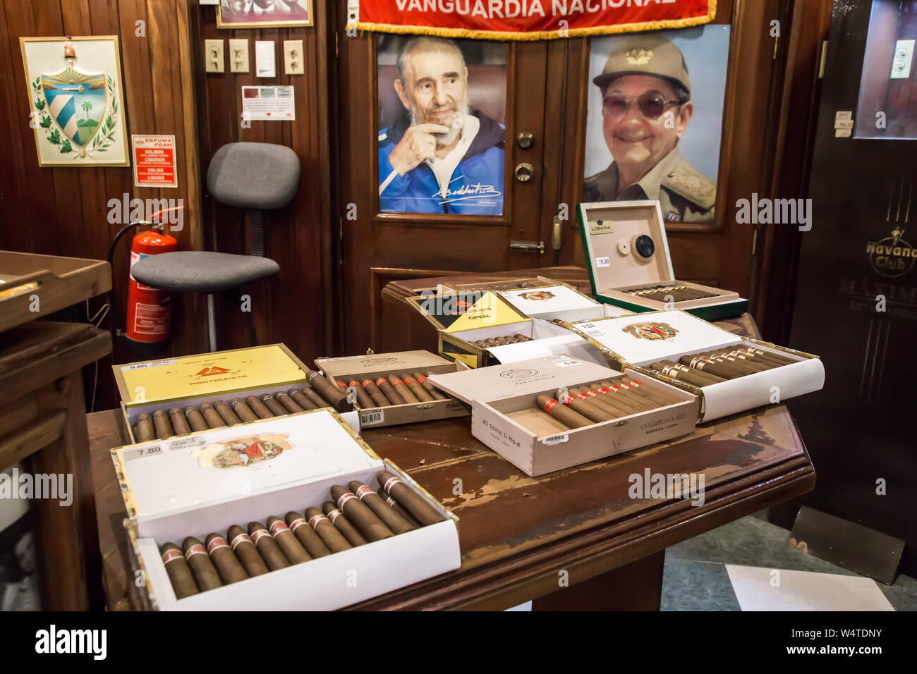 Tavolo pieno di scatole di sigari in Romeo y Julieta cigar shop. Foto di Fidel e Raul Castro in background. Foto Stock