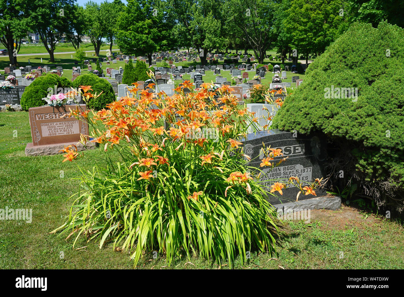 Un paese pittorica cimitero vicino Sherburne, Ontario, Canada con un sacco di fiori e di Nizza cantieri grave Foto Stock