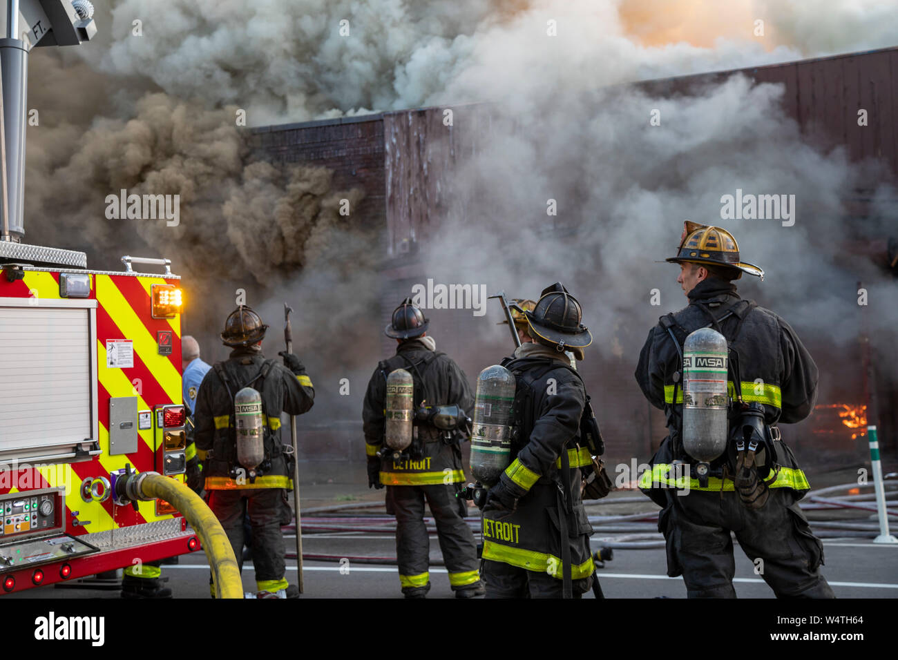 Detroit, Michigan - Vigili del Fuoco attendere prima di entrare in un ardente, a lungo vacanti in centro di struttura. La costruzione di una volta alloggiata l'oro dollaro, un club whic Foto Stock