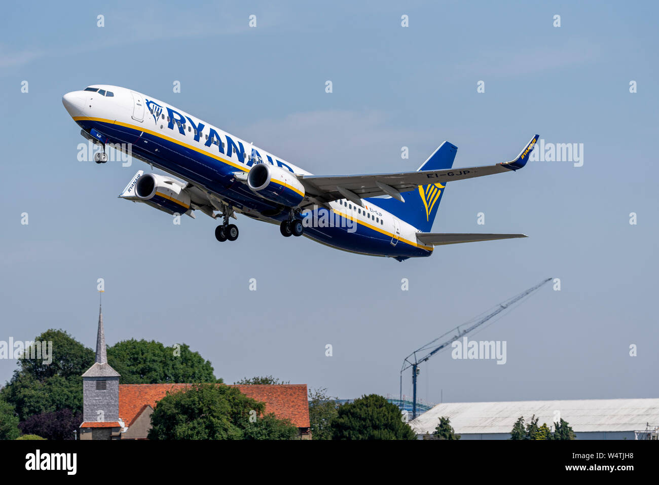 Ryanair Boeing 737 aereo jet piano EI-GJP decollare da Londra aeroporto di Southend, Essex, Regno Unito al di sopra di costruzione Lavori di costruzione, gru e chiesa Foto Stock