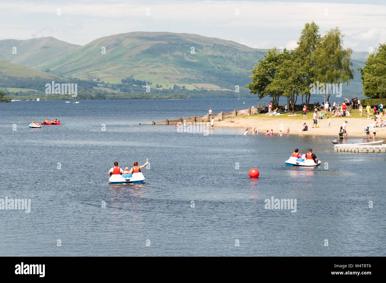 Loch Lomond Shores, Balloch, Scotland, Regno Unito - 25 Luglio 2019: Regno Unito - previsioni del tempo - Come temperature aumento a 28 gradi famiglie prendere l'acqua, godendo di pedalò e gite in barca sul Loch Lomond a Loch Lomond Shores Credito: Kay Roxby/Alamy Live News Foto Stock