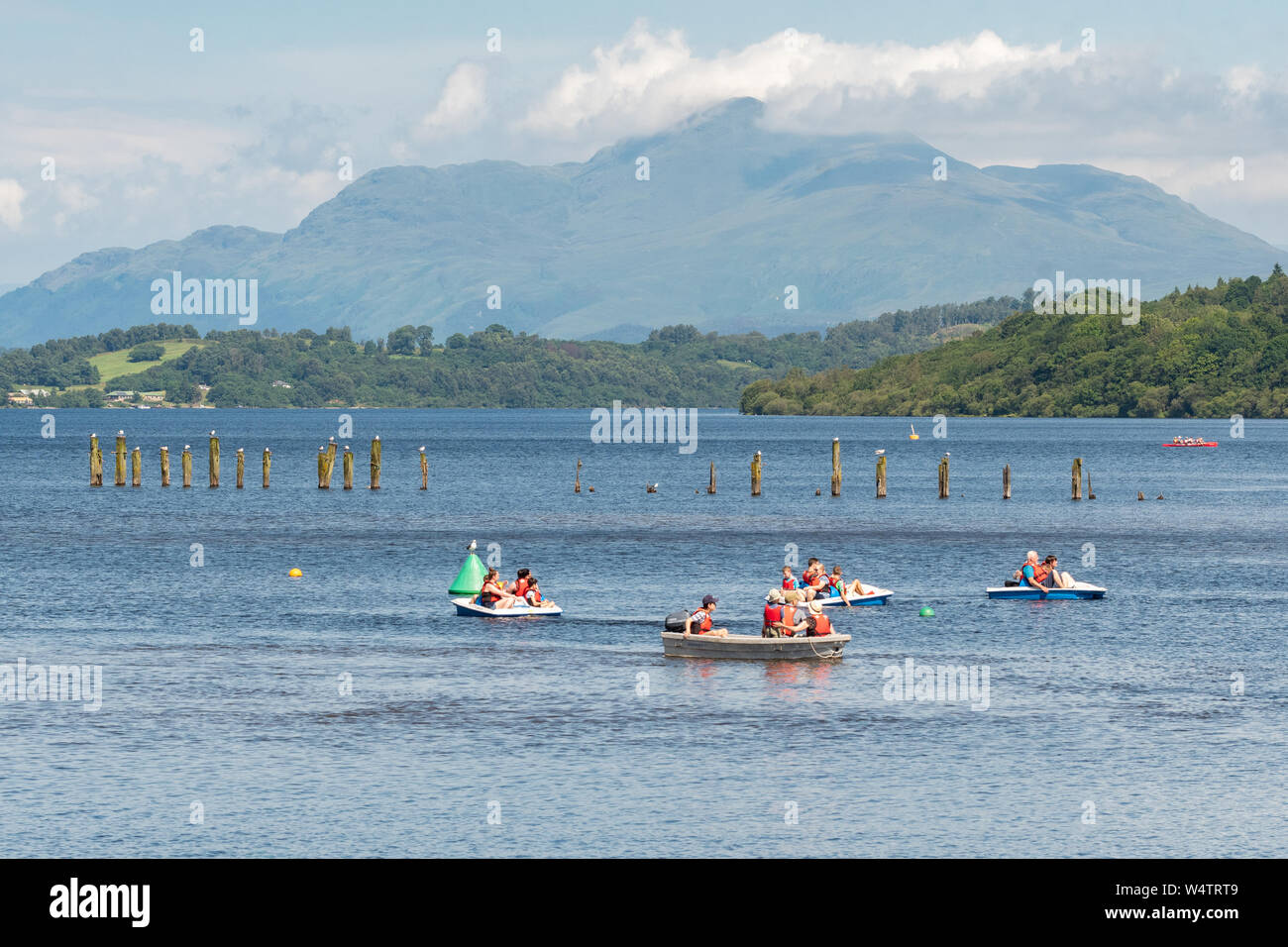 Loch Lomond Shores, Balloch, Scotland, Regno Unito - 25 Luglio 2019: Regno Unito - previsioni del tempo - Come temperature aumento a 28 gradi famiglie prendere l'acqua, godendo di pedalò e gite in barca sul Loch Lomond a Loch Lomond Shores, contro il sole sullo sfondo di Ben Lomond. Credito: Kay Roxby/Alamy Live News Foto Stock
