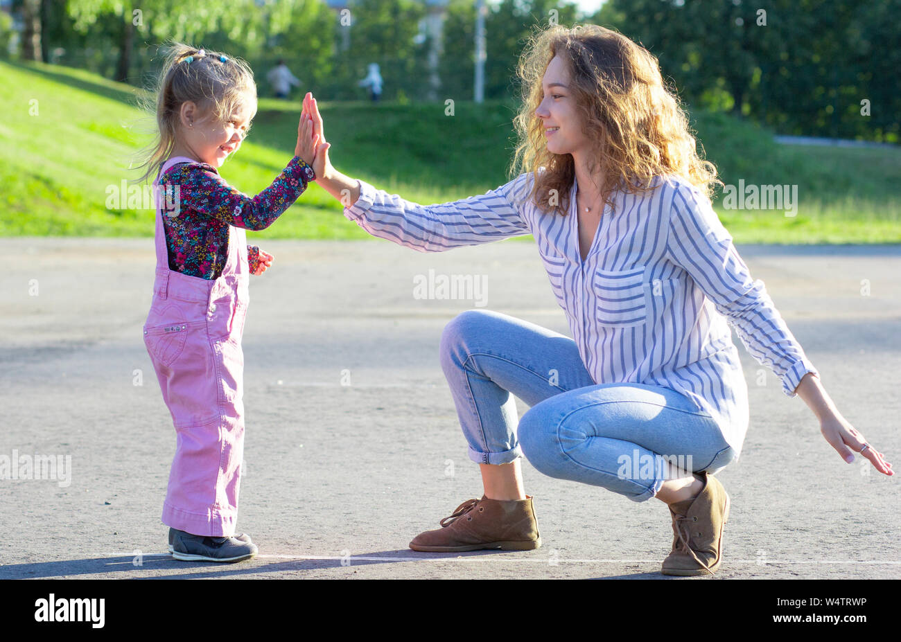 Felice giovane donna seduta a giocare con la bambina battendo le mani Foto Stock