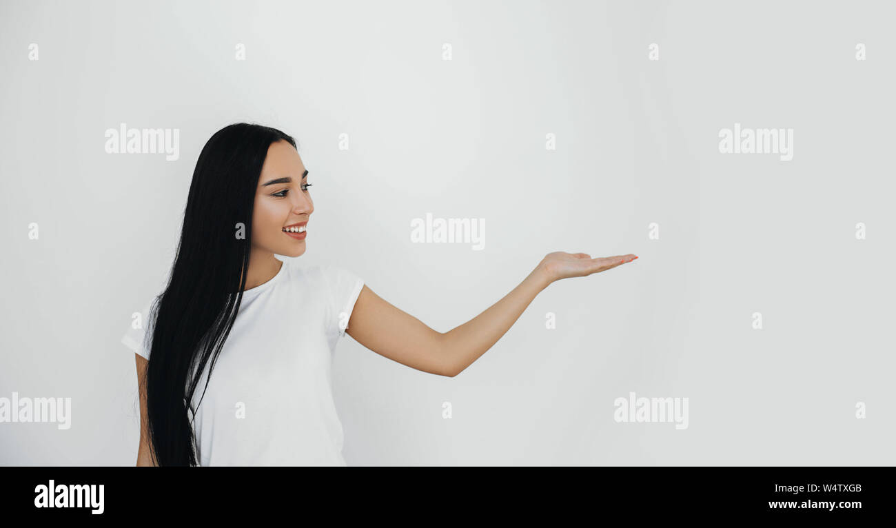 Brunette donna prodotto pubblicitario puntando la mano nella copia di sfondo spazio. Foto Stock
