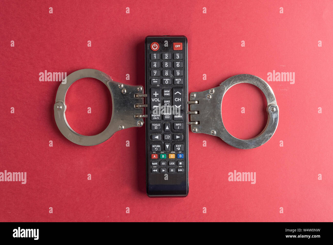 TV concetto di dipendenza con il telecomando della tv con manette Foto Stock