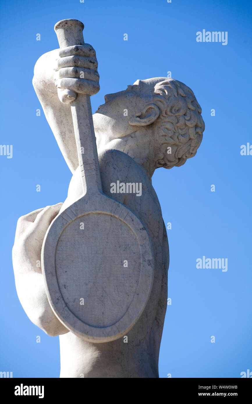 Una statua di pietra di un giocatore di tennis in Stadio dei Marmi (Marmo Stadium) in Roma. La statua ha il suo braccio sollevato per servire contro un Cielo di estate blu. Foto Stock