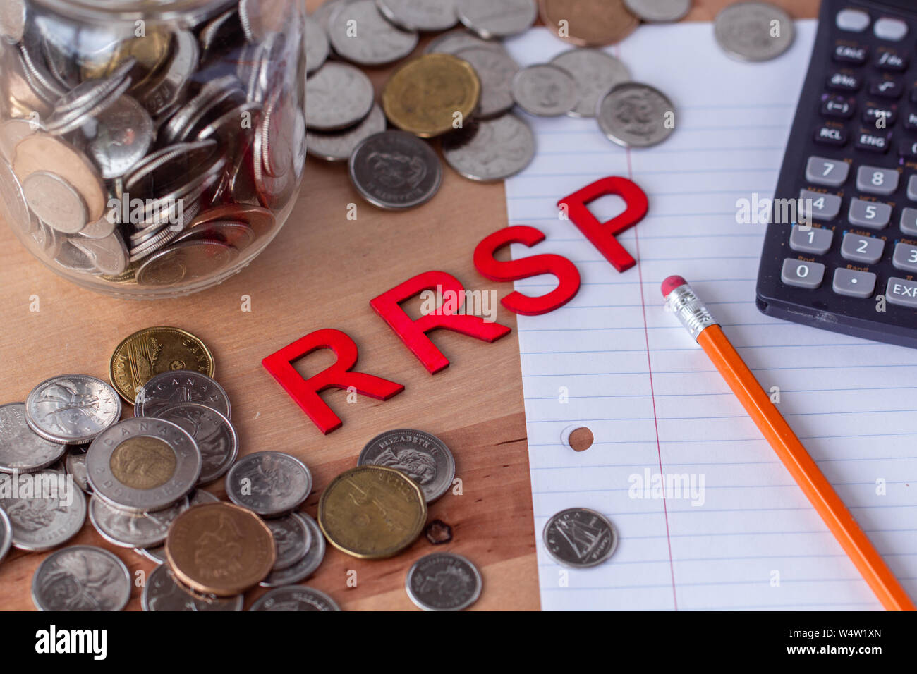 RRSP' (registrati Piano di risparmio previdenziale) enunciato nella lettera in legno piastrelle con denaro, carta, matita e calcolatrice che circonda la parola. Foto Stock