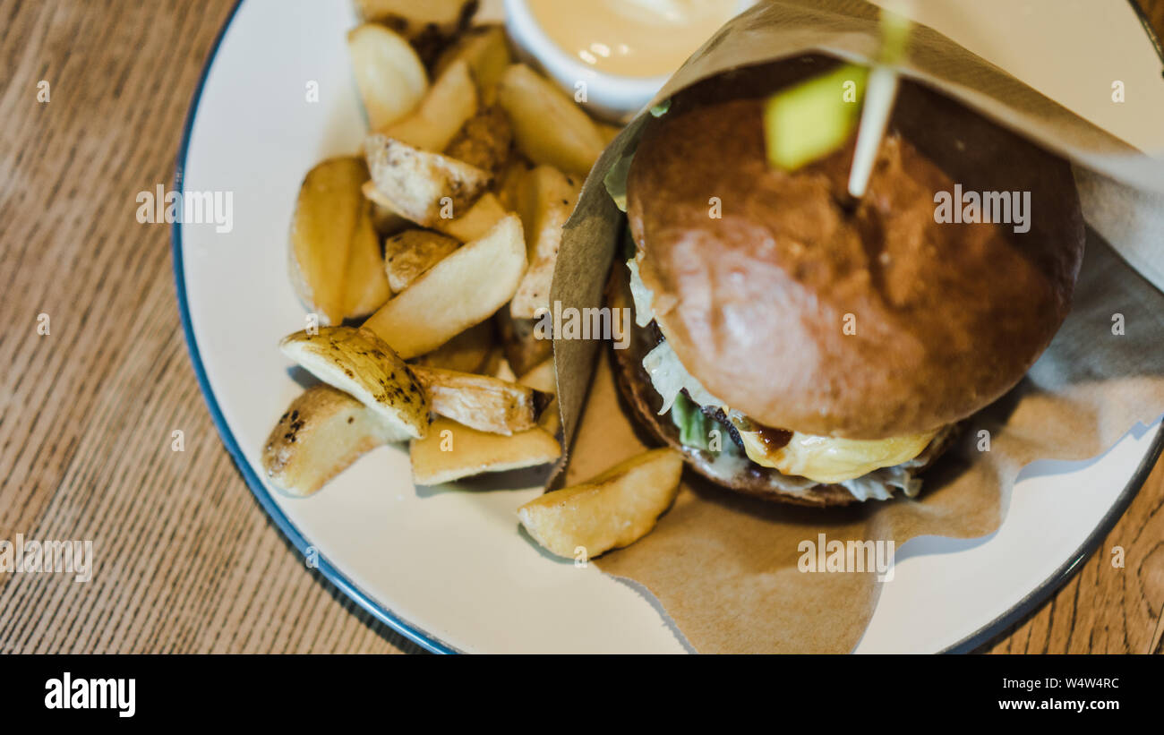 Un fresco e gustoso, succosa hamburger con formaggio, pomodori stagionati carni bovine in marmo, lattuga fresca, salsa maionese e patate sul tavolo di legno . Foto Stock