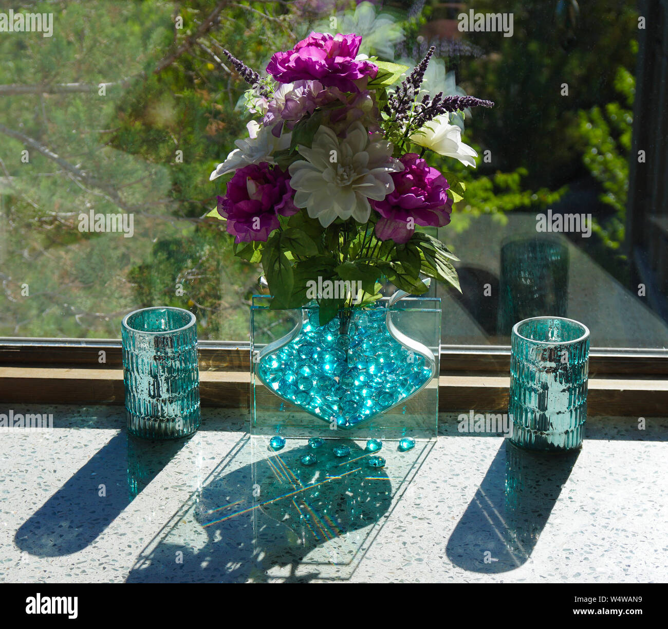 Bouquet di fiori in un vaso di vetro crea riflessi e ombre Foto Stock