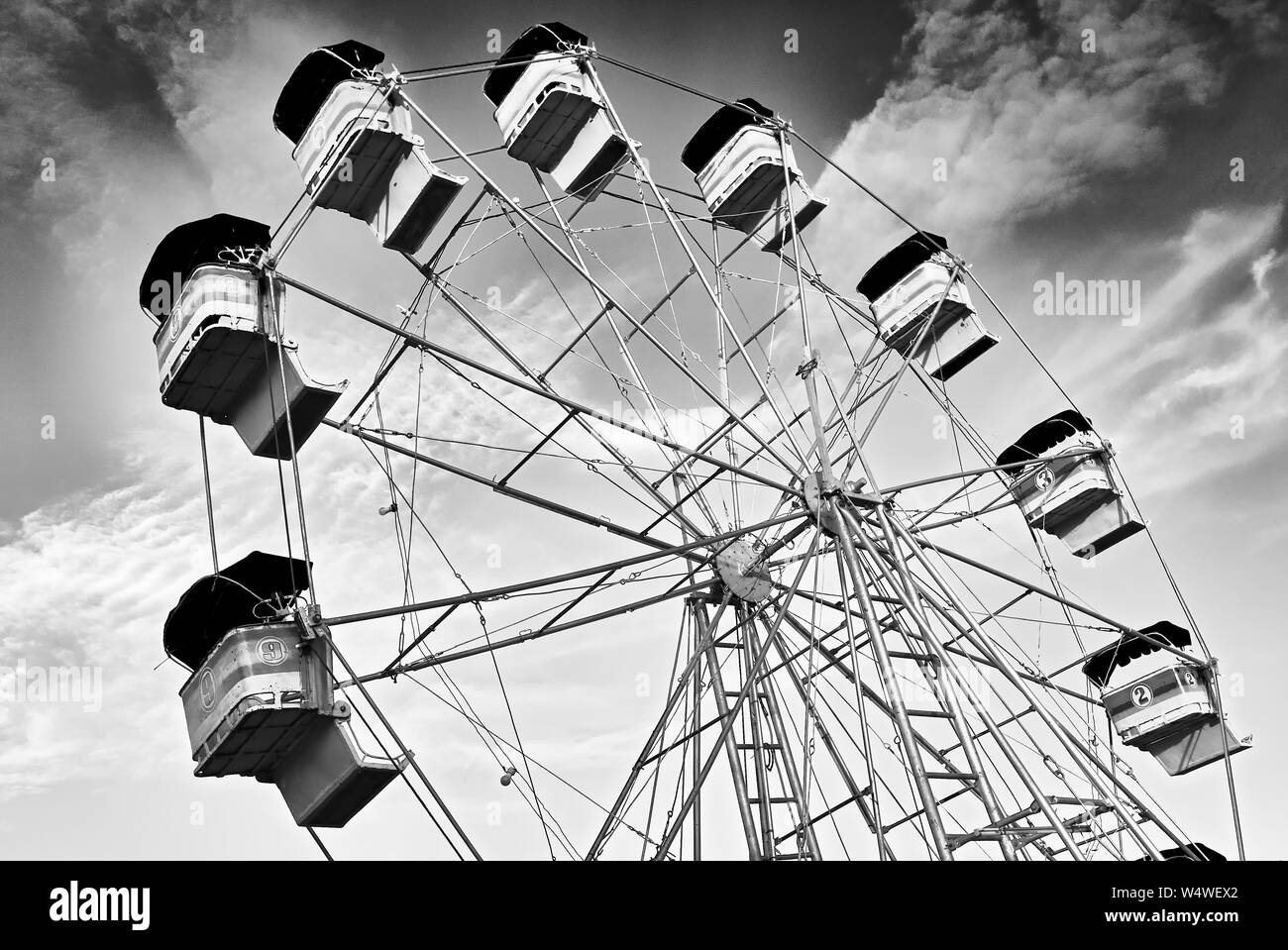 In stile retrò ruota panoramica Ferris in bianco e nero contro un drammatico cielo con nuvole a un carnevale in città Cuertero, Capiz Provincia, Filippine. Foto Stock