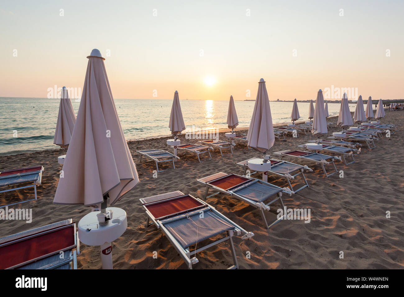 Chiuso ombrelloni e sedie in un bel tramonto. il cielo è rosso e arancione. Concetto di vacanza. Foto Stock