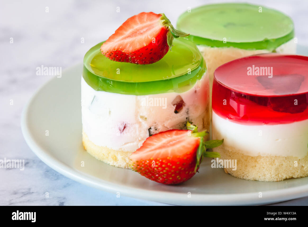 Mini rotonda la cheesecake a freddo con gelatina di frutta e le fragole. Foto Stock