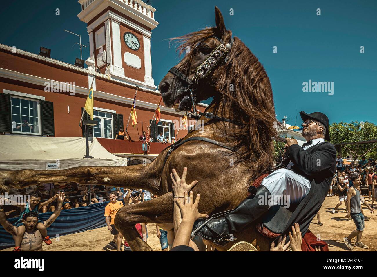 Es Castell, Spagna. 25 Luglio 2019: un 'caixer' (cavallo Cavaliere) culatte fino sul suo cavallo circondato da un tifo folla durante il tradizionale "Jaleo al Sant Jaume Festival in Es Castell Credito: Matthias Oesterle/Alamy Live News Foto Stock