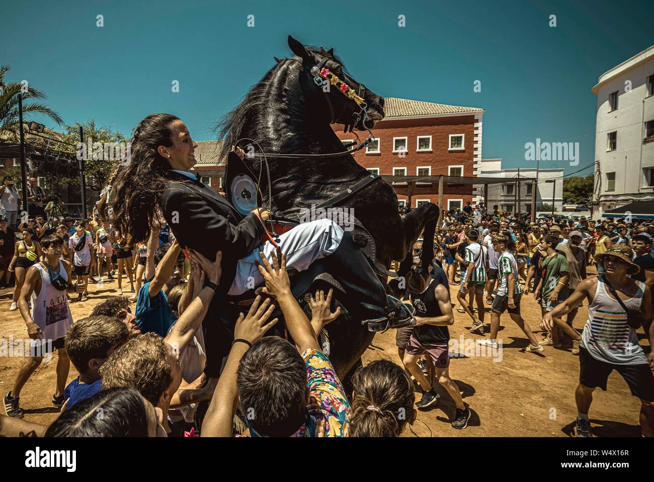 Es Castell, Spagna. 25 Luglio 2019: un 'caixer' (cavallo Cavaliere) culatte fino sul suo cavallo circondato da un tifo folla durante il tradizionale "Jaleo al Sant Jaume Festival in Es Castell Credito: Matthias Oesterle/Alamy Live News Foto Stock