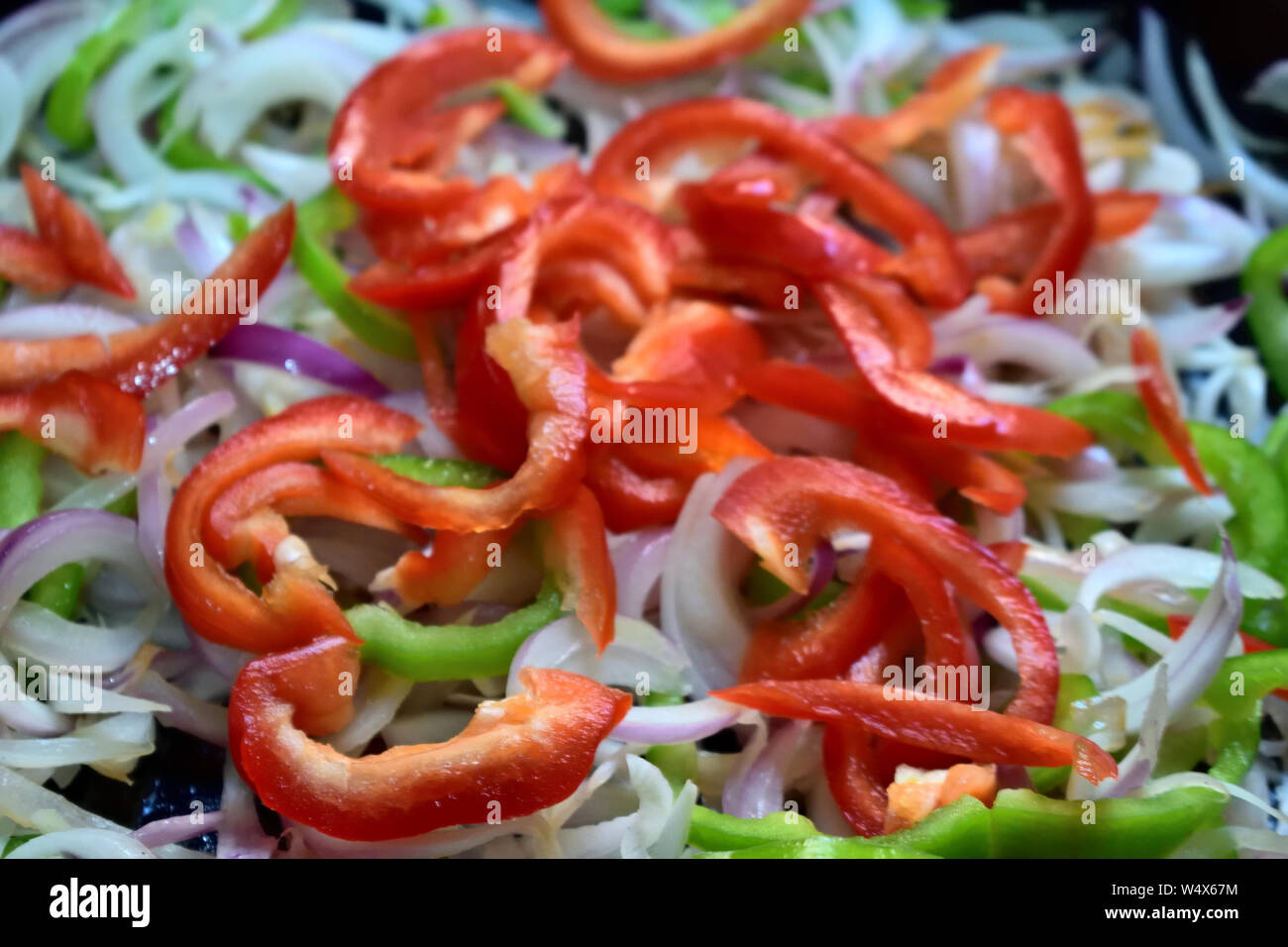 foto non edita di peperone verde e rosso fresco tagliato a fette con cipolla su piatto Foto Stock