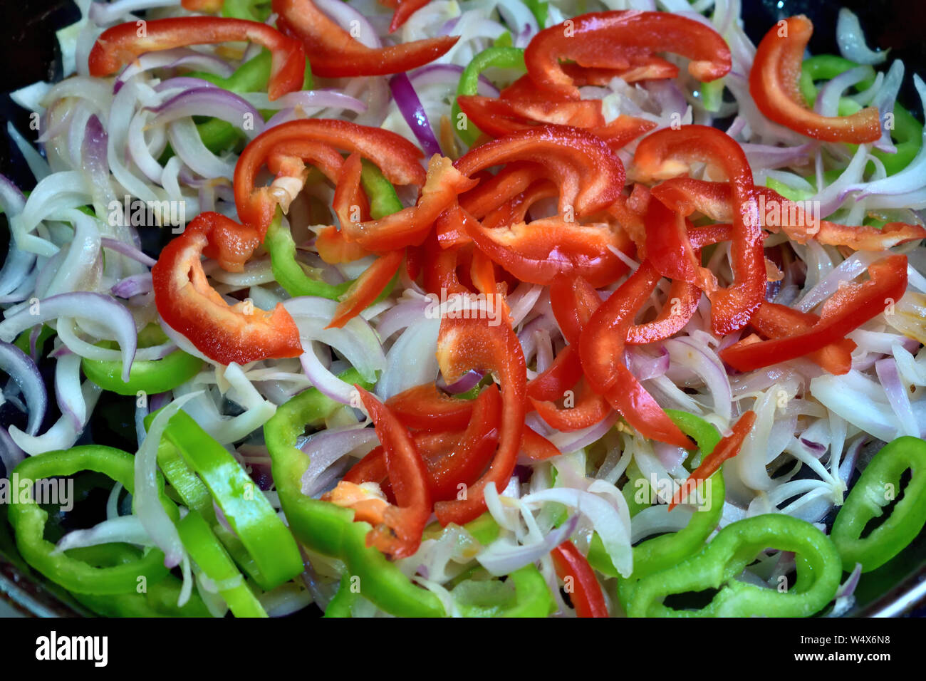 foto non edita di peperone verde e rosso fresco tagliato a fette con cipolla su piatto Foto Stock