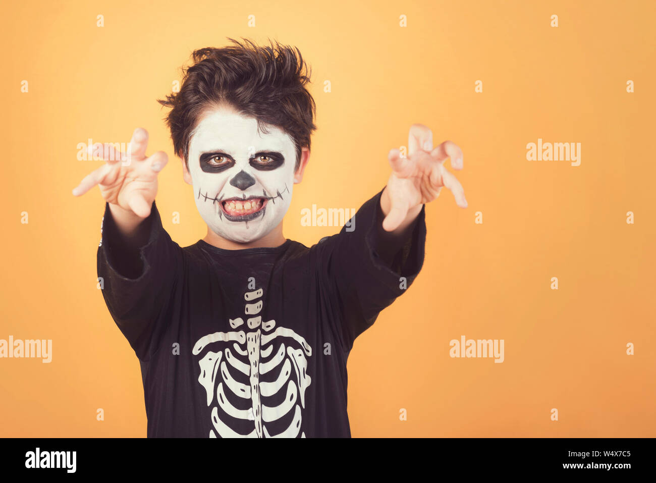 Happy Halloween. divertente bambino in un costume di scheletro di halloween su sfondo arancione Foto Stock