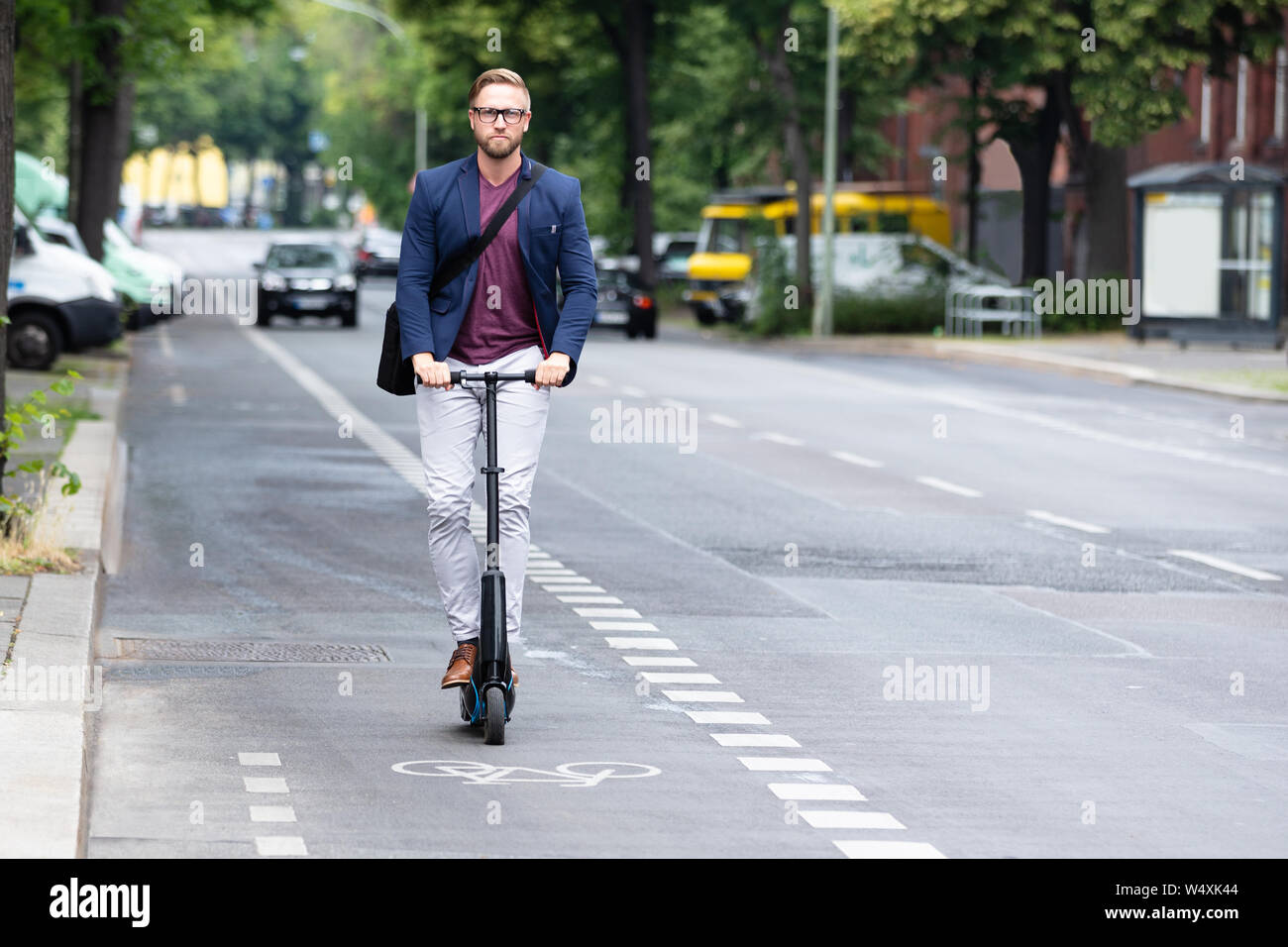 Ritratto di un giovane imprenditore Riding Scooter elettrico sulla strada in città Foto Stock