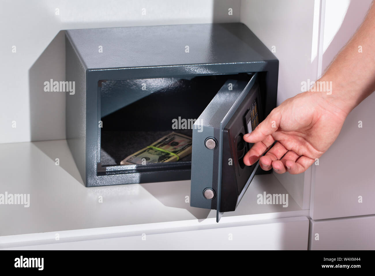 Una mano d'uomo mettendo Bundle di banconota in una cassetta di sicurezza Foto Stock
