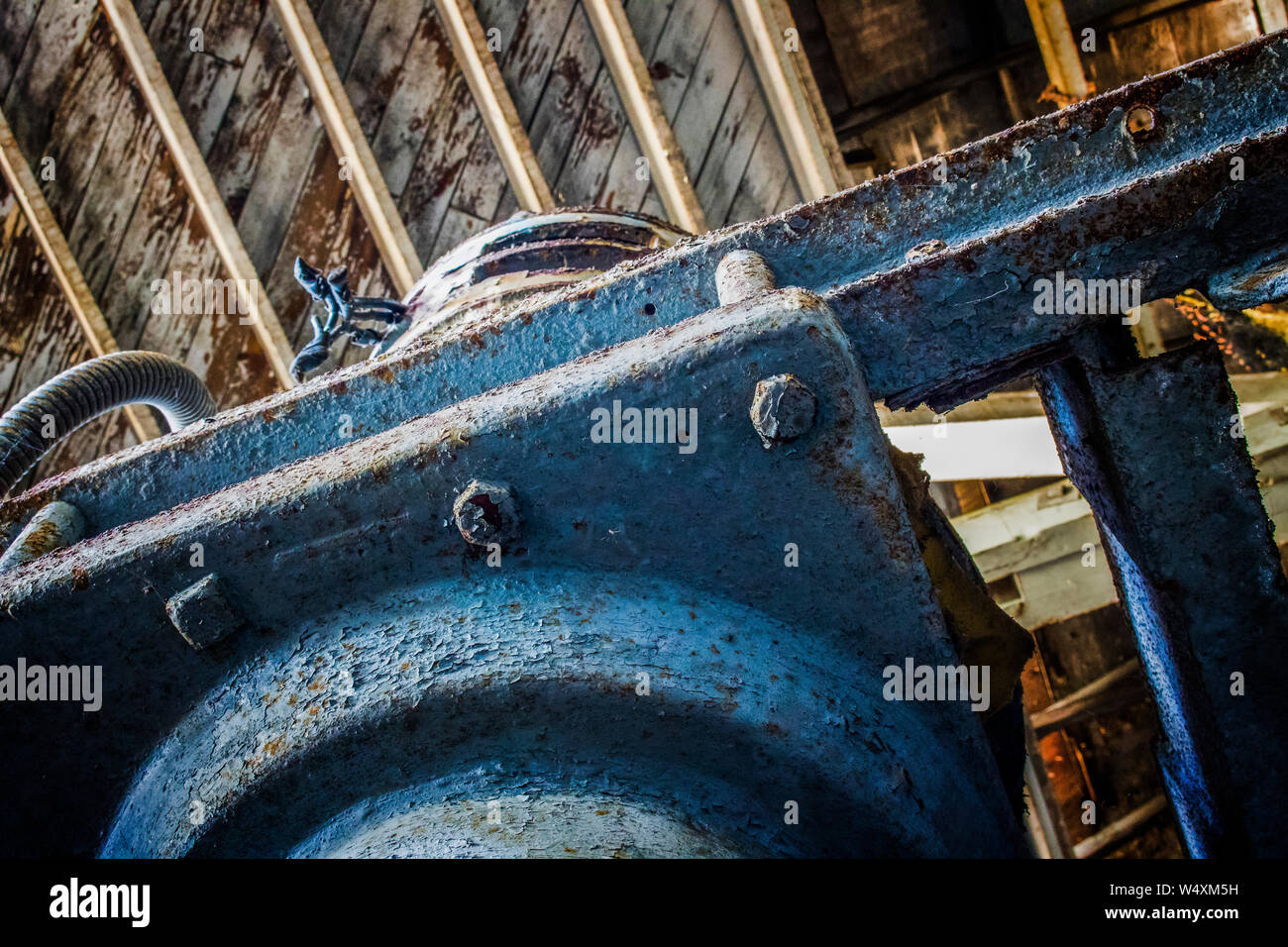 Dettaglio dei vecchi macchinari arrugginiti e bulloni all peeling vernice blu sotto il soffitto in legno. Foto Stock
