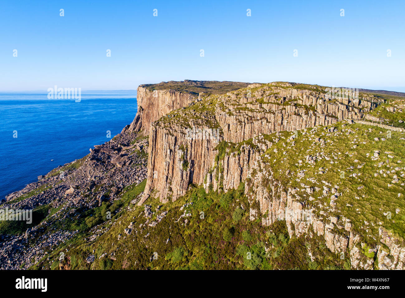 Fair Head big cliff e operazioni automatiche di fine campo all'angolo nord-est della Contea di Antrim. Irlanda del Nord, Regno Unito. Famoso luogo di arrampicata. Vista aerea in sunset paglierino Foto Stock