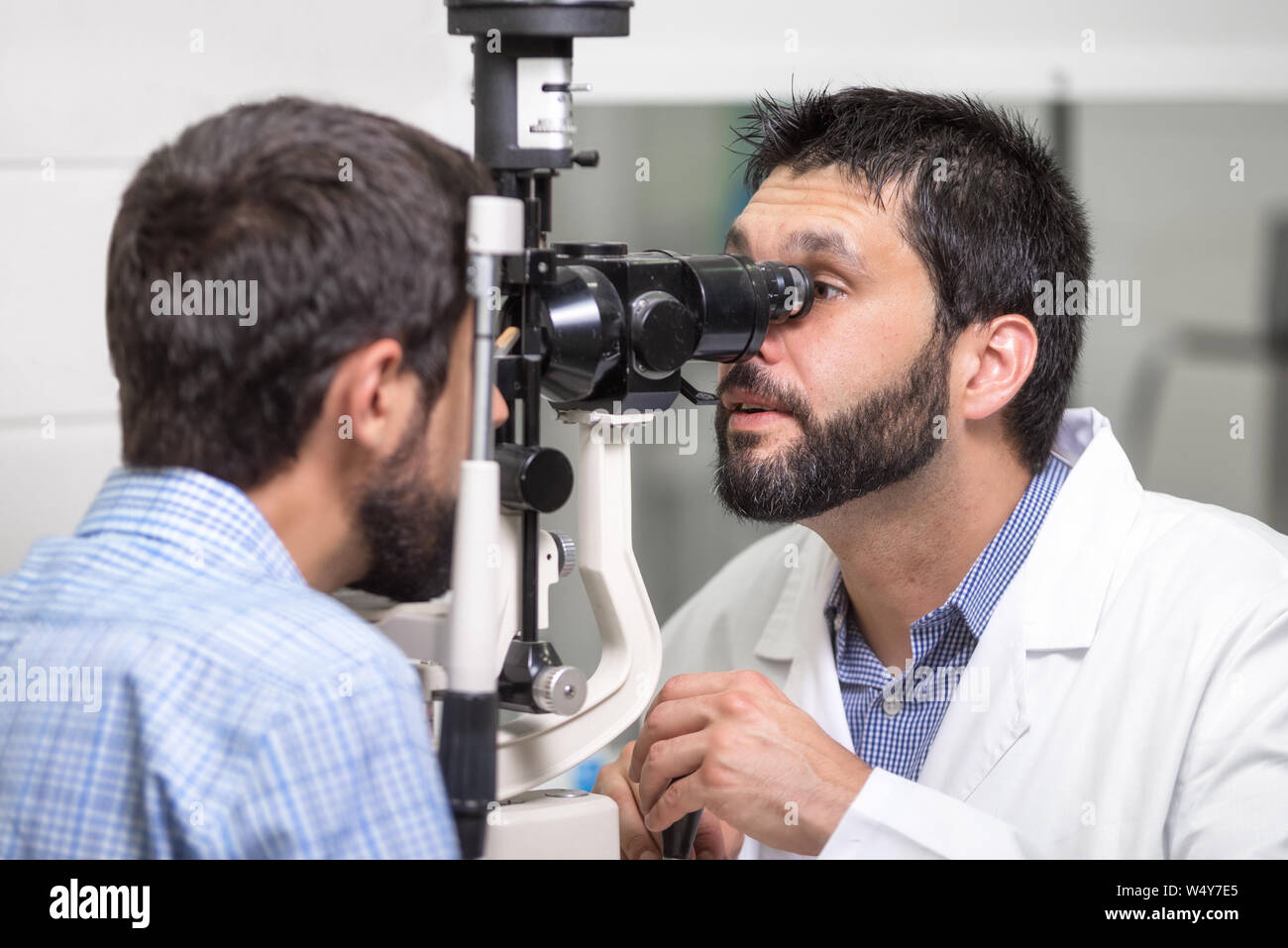 Voce maschile medico oculista è controllare la visione del bel giovane in clinica moderna. Il medico e il paziente in Oftalmologia Clinica . Foto Stock